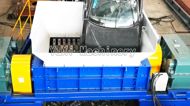 Large double shaft shredder being fed a whole waste car for primary crushing.