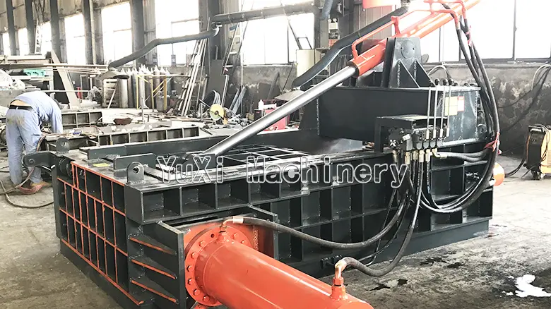 Hydraulic scrap metal baler operating in an industrial workshop